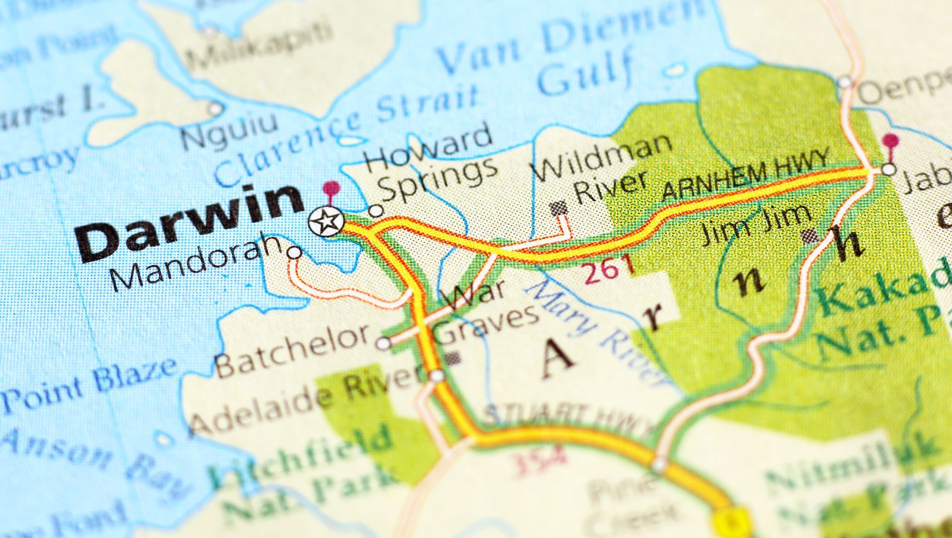 Three construction workers in hard hats looking at a laptop and blueprints on a construction site.