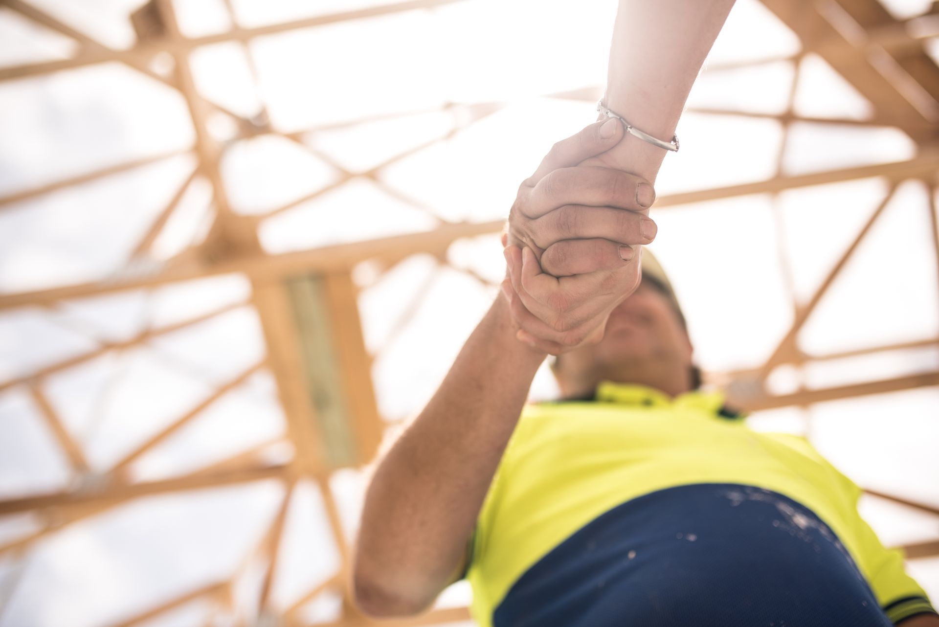 Two construction workers wearing hard hats, reviewing blueprints at a construction site.