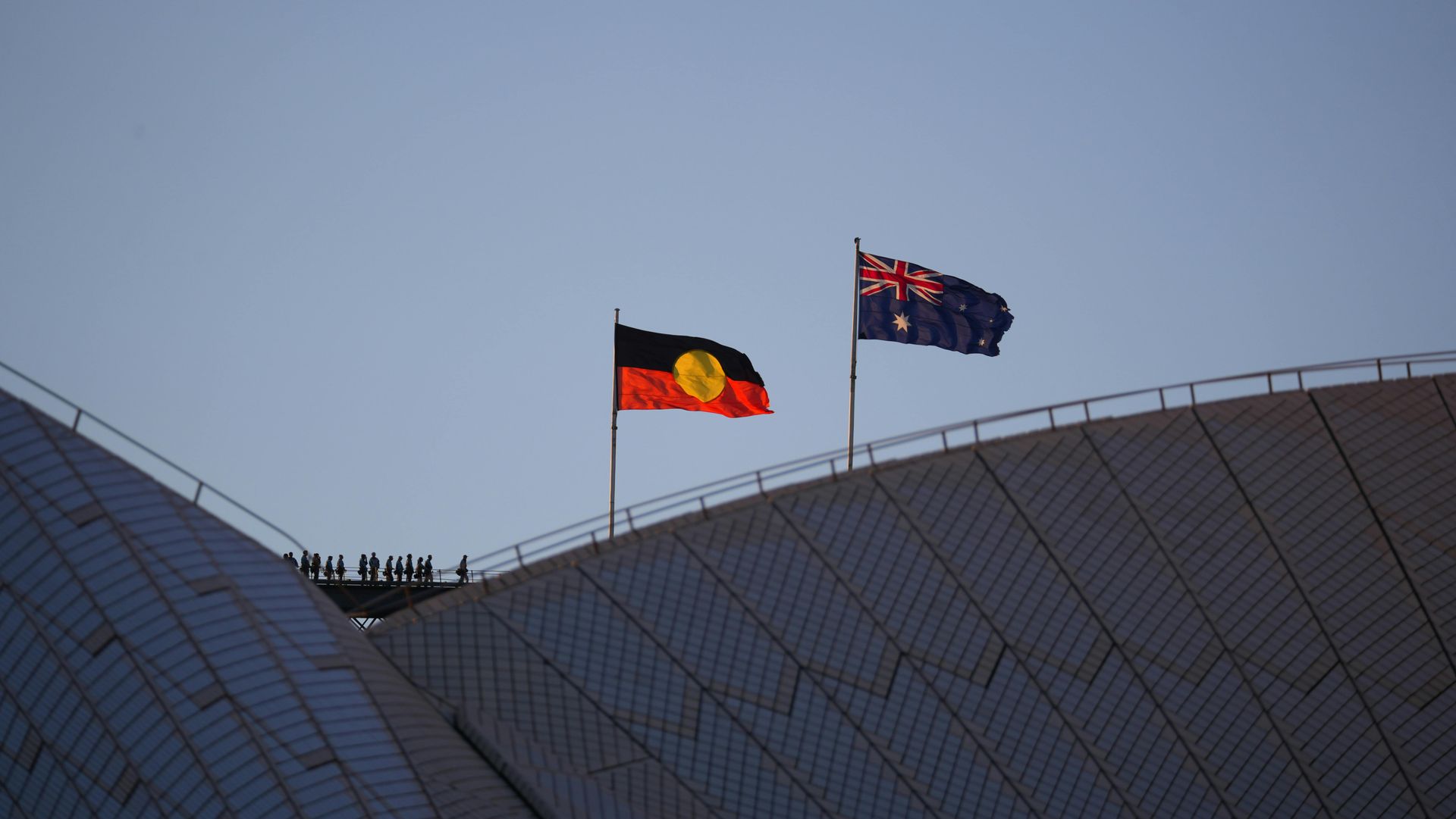 Two construction workers wearing hard hats, reviewing blueprints at a construction site.