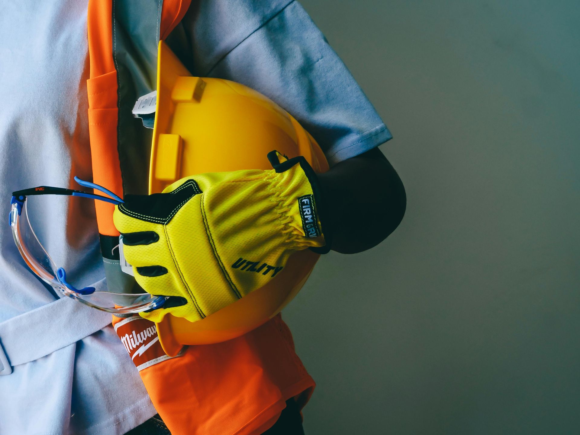 Two people in hard hats and suits review documents on a clipboard at a construction site.