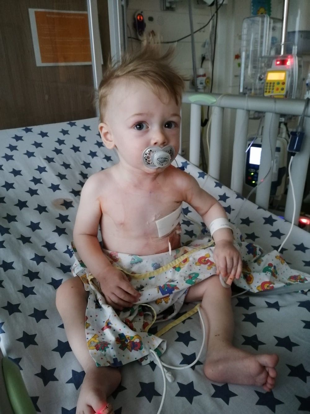 Website Sorted Three Peaks Challenge | A baby is sitting in a hospital bed with a pacifier in his mouth