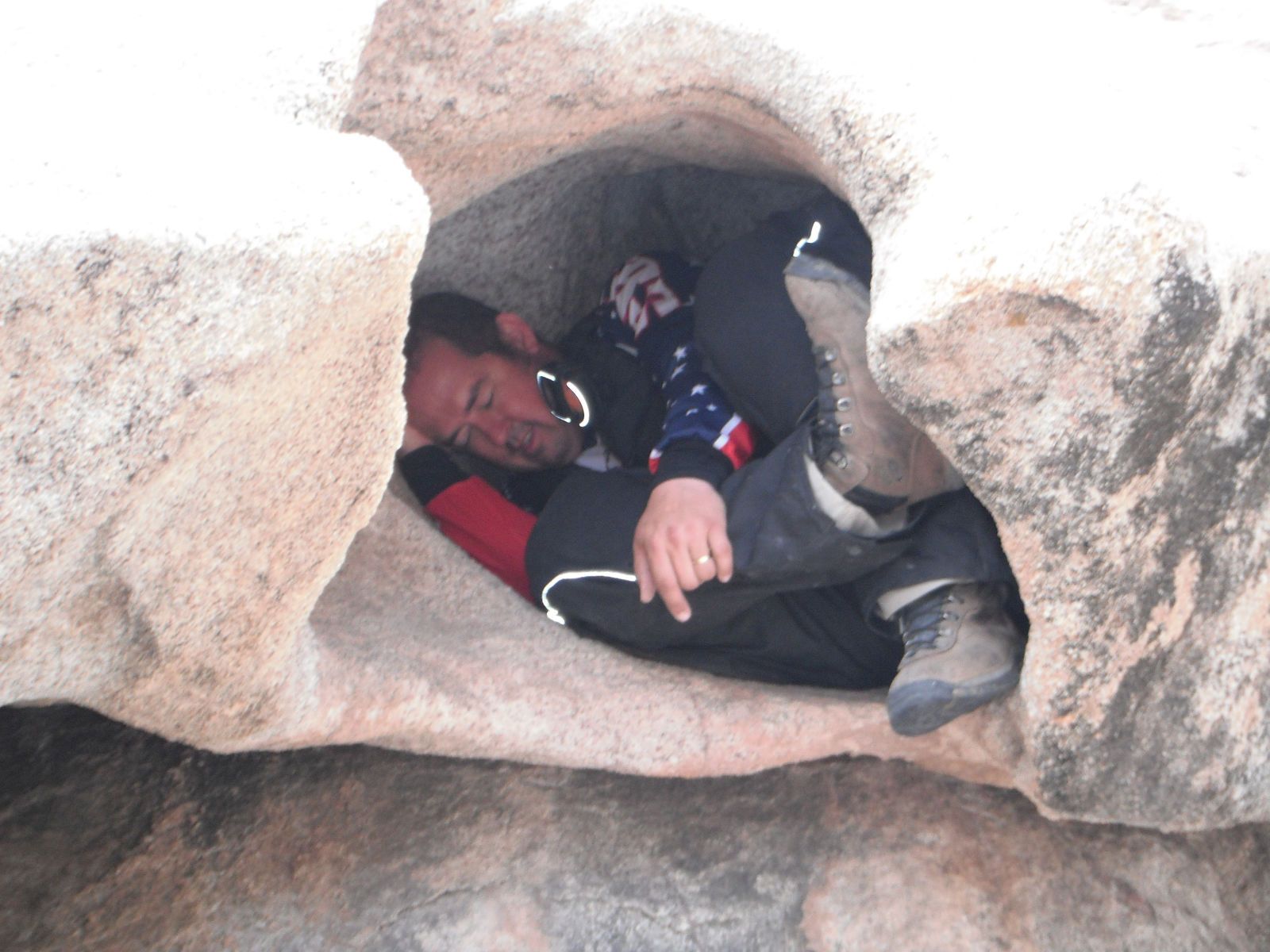 A man is sleeping in a cave with the number 93 on his shirt