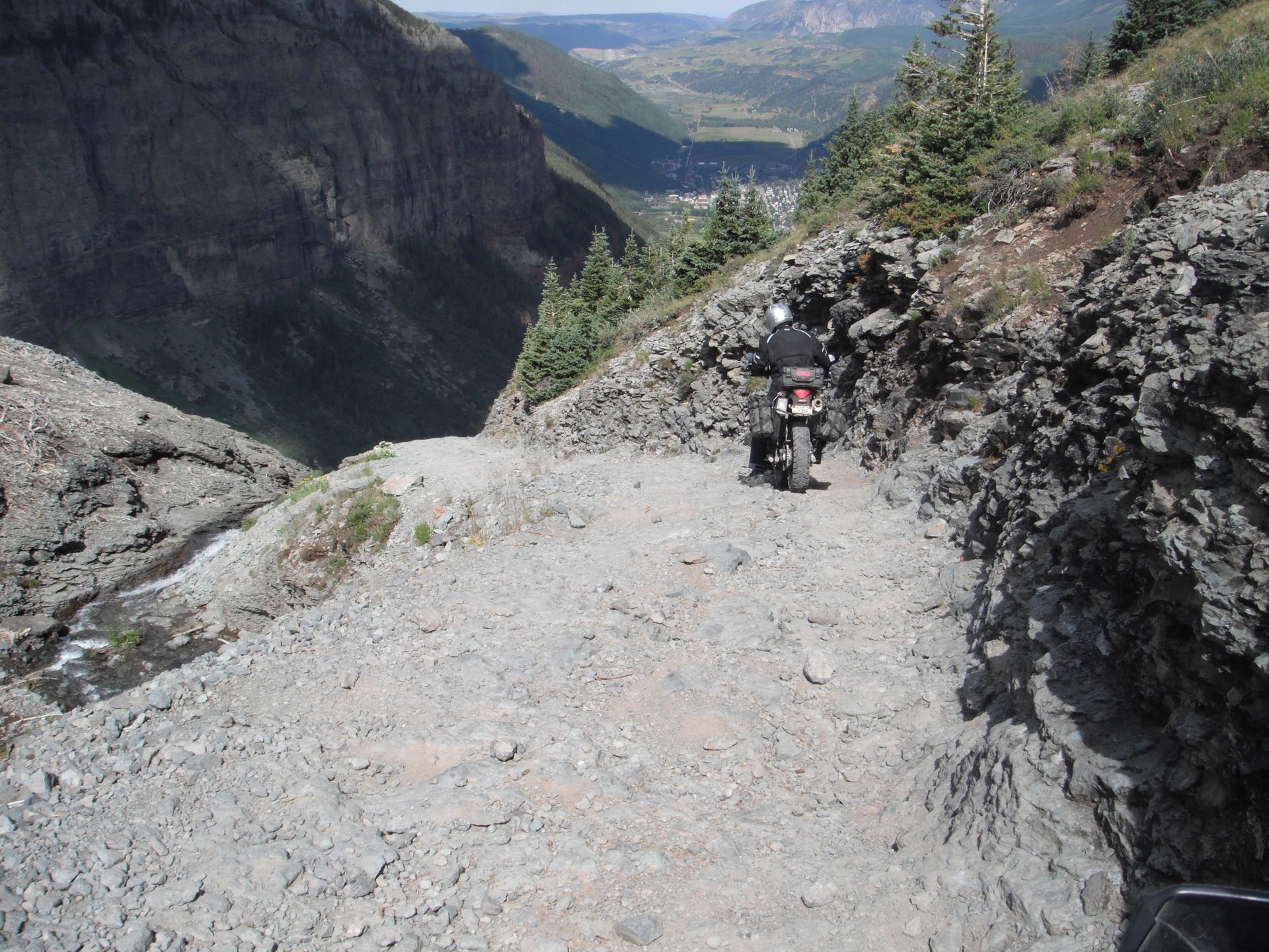 A person riding a motorcycle down a dirt road in the mountains