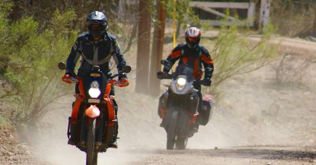 Two people riding a motorcycle through the desert