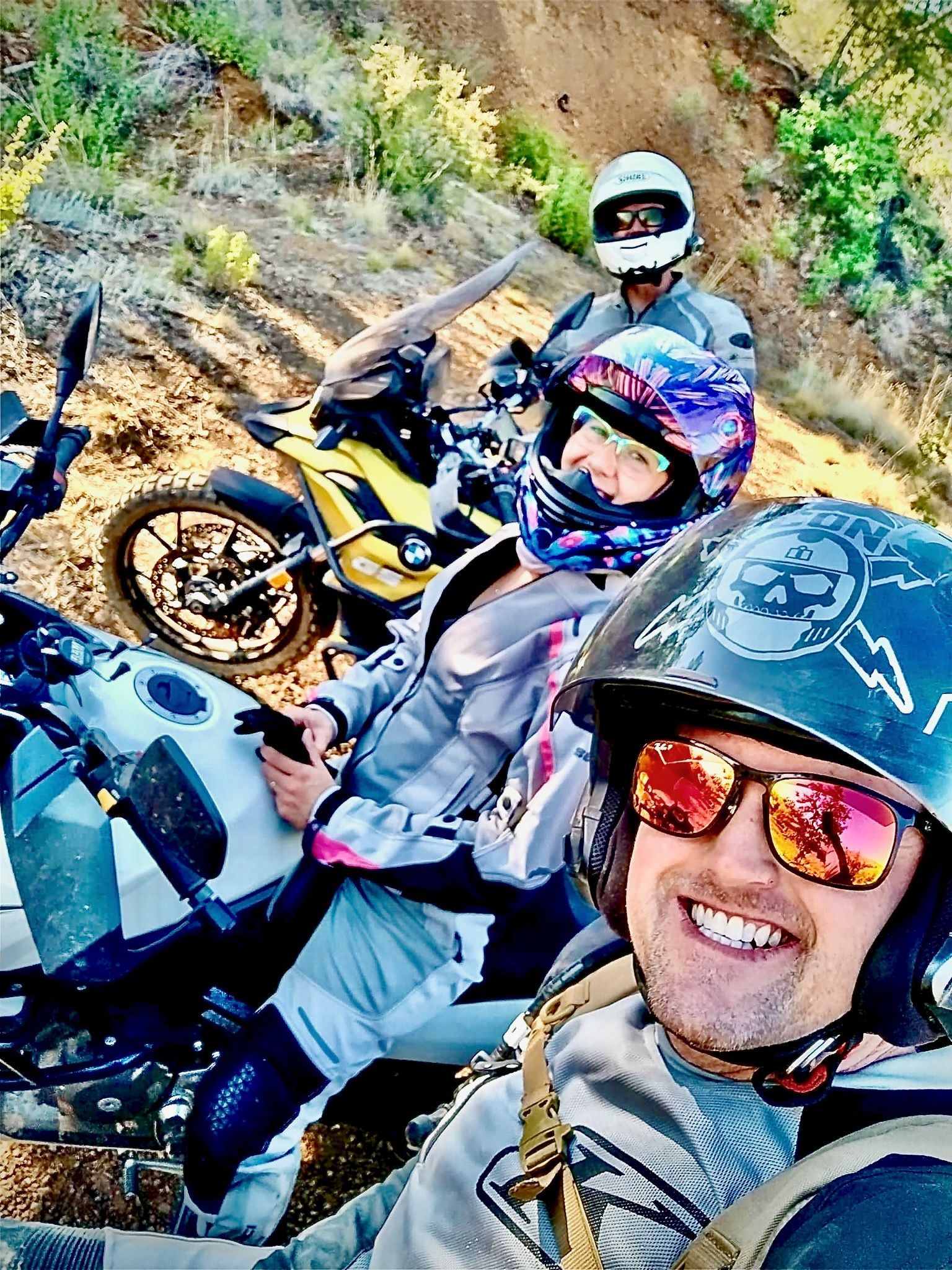 People on motorcycles wearing helmets and sunglasses, smiling for the camera.