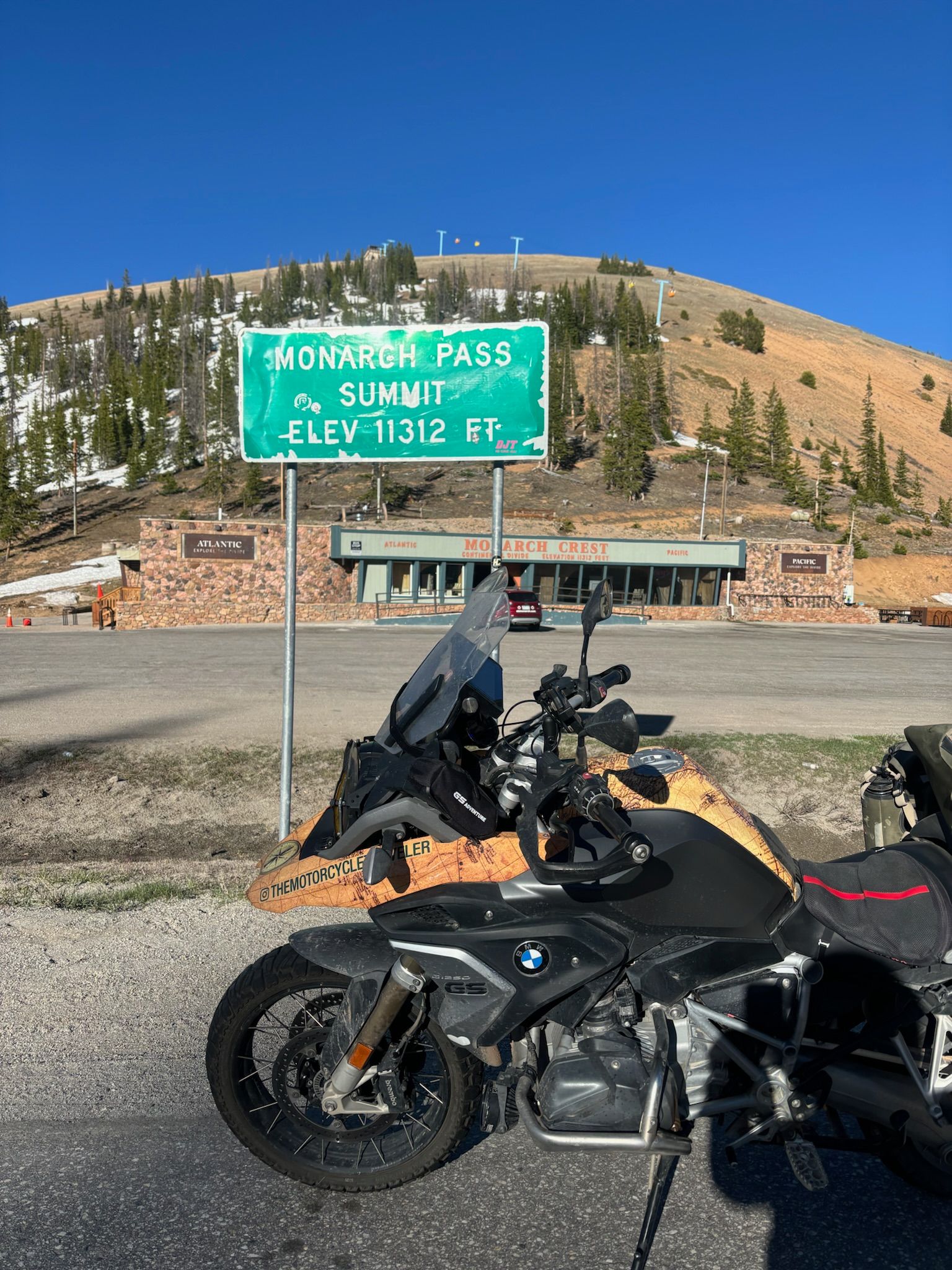 Two motorcycles are parked in front of a sign that says mcalpine pass.
