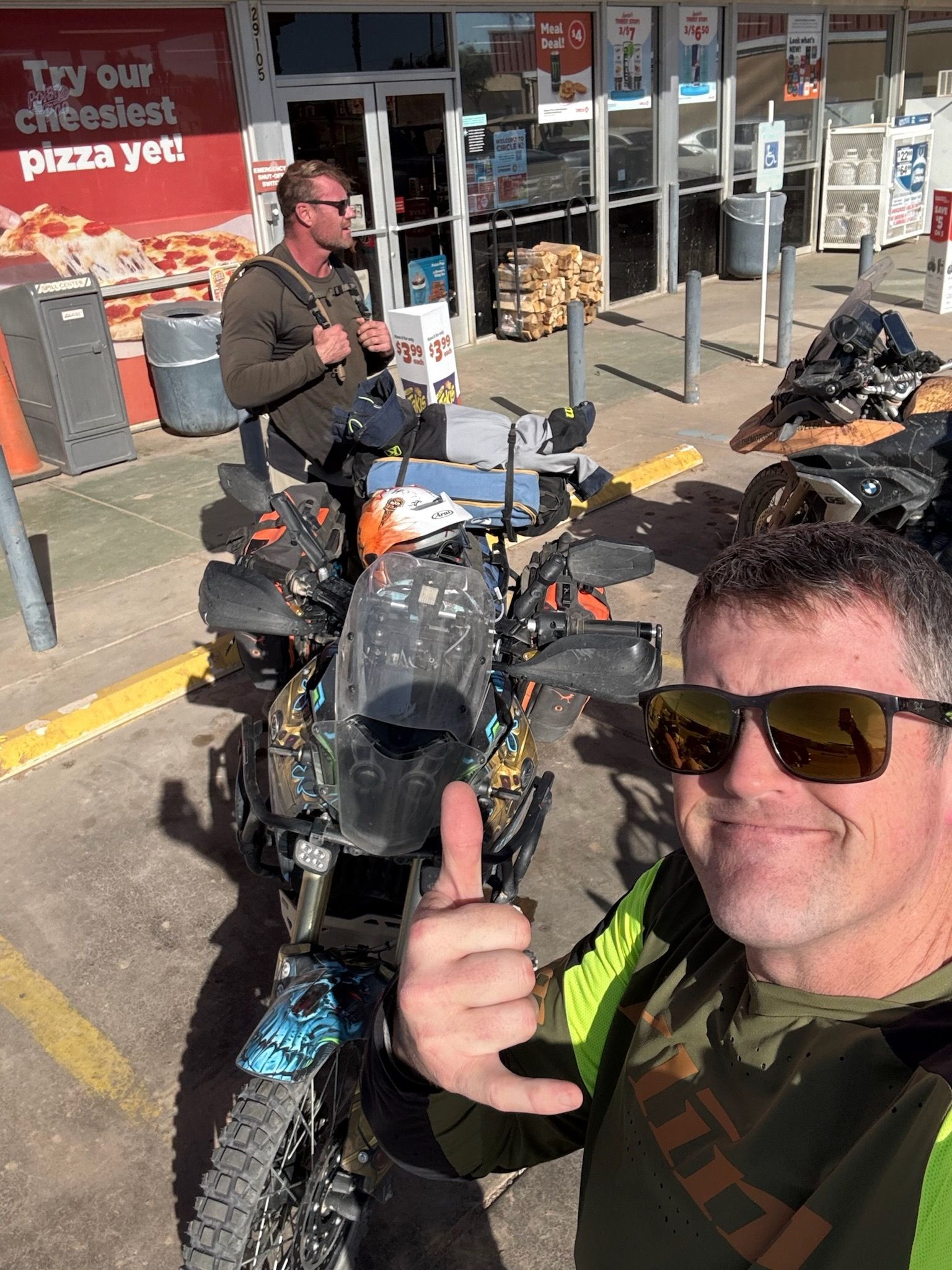 Man giving a thumbs up in front of parked motorcycles