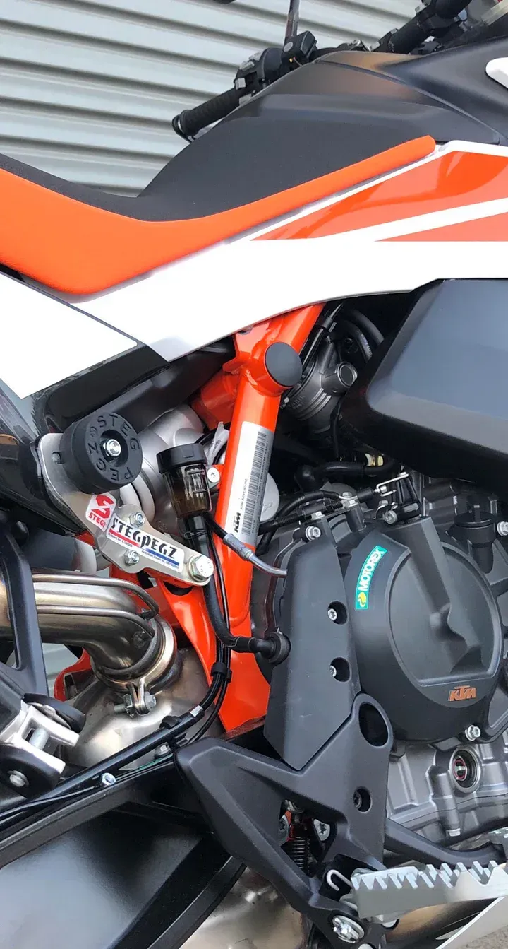 A close up of the engine of a motorcycle installed with Steg Pegz.