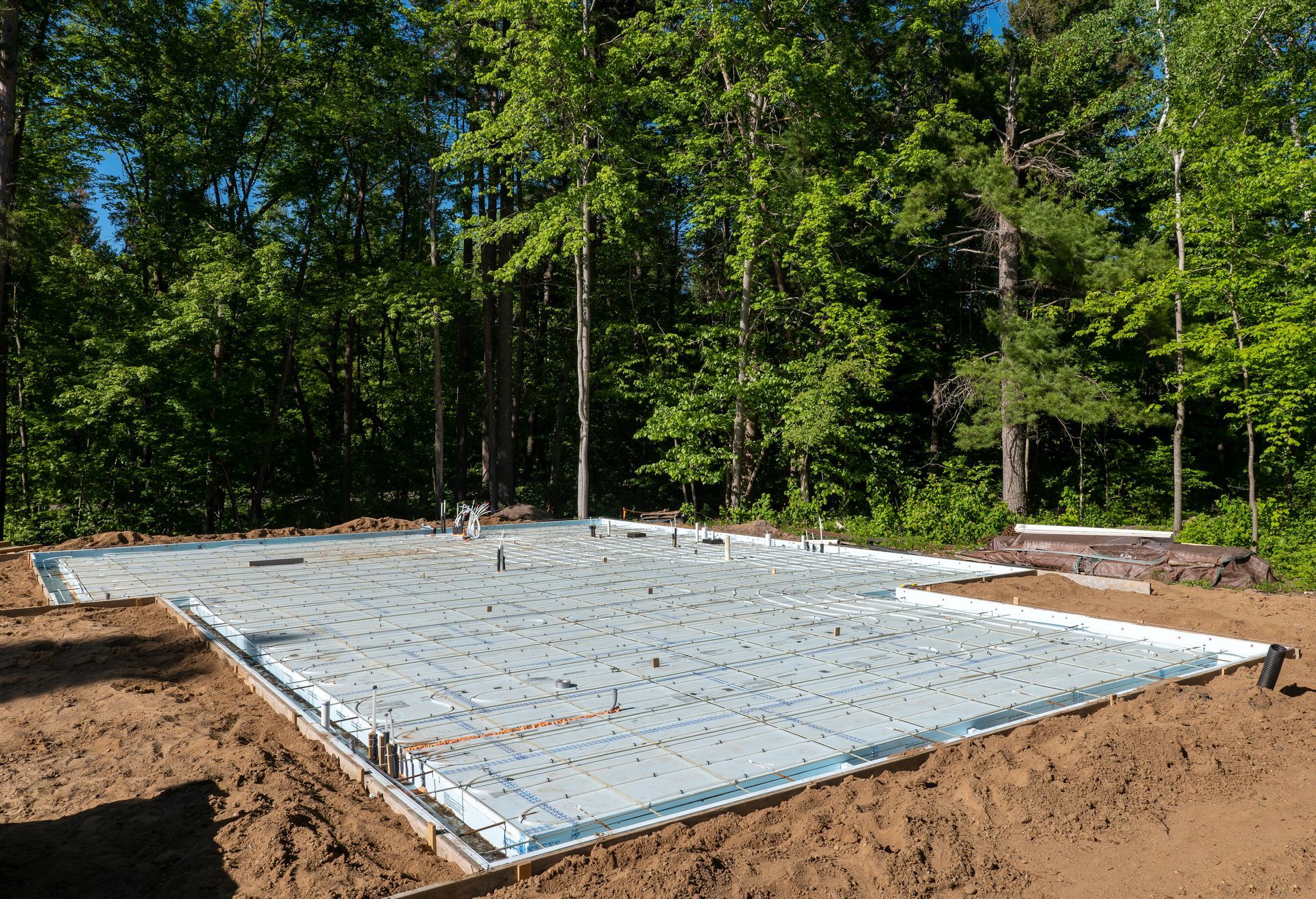 A construction site with foam insulation and underfloor heating tubes, preparing for the concrete slab floor.