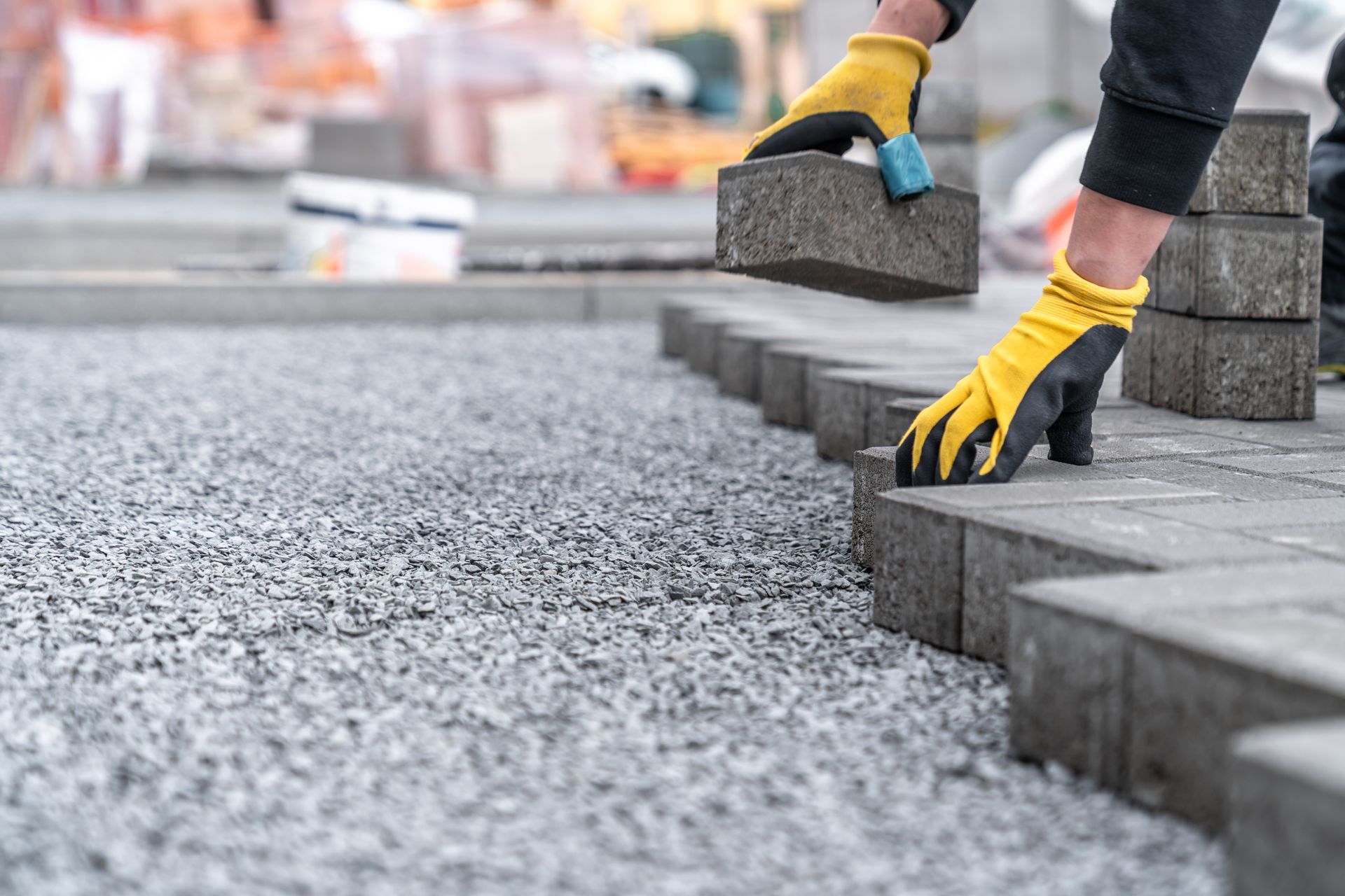 Workers installing interlocking pavers for sidewalks and roads during construction.