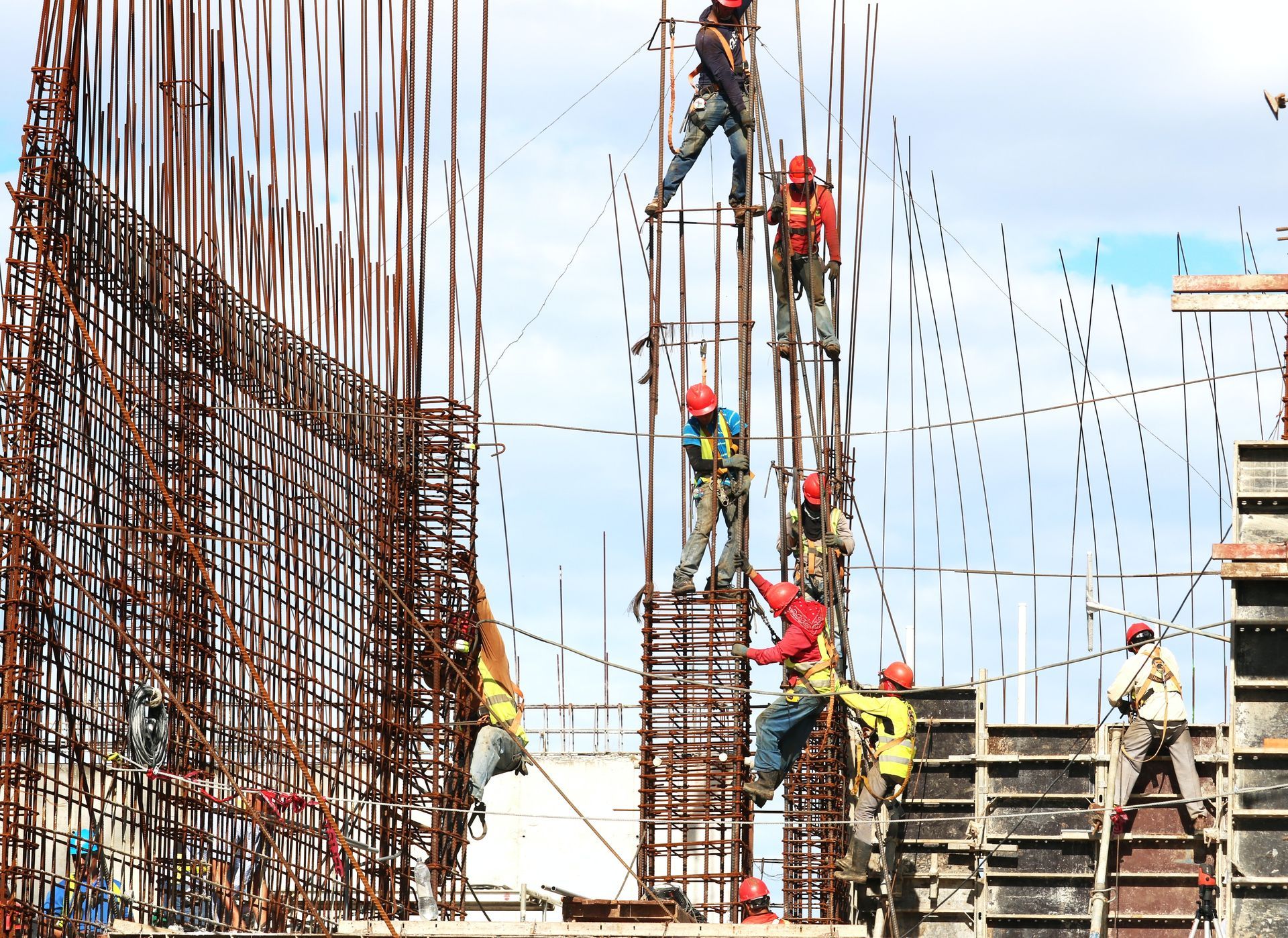 Construction workers in hard hats and vests assembling a new building structure.