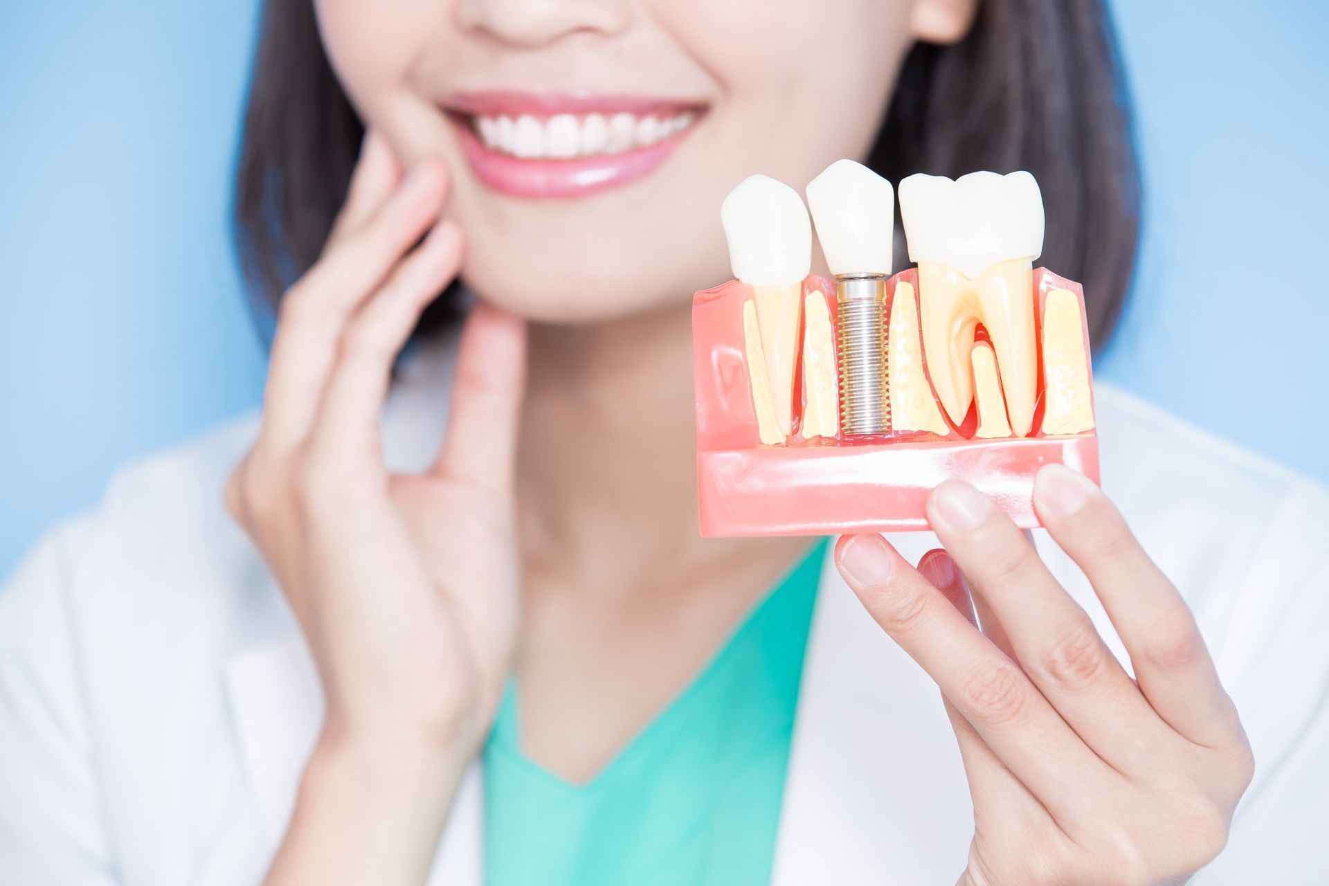 Person holding a dental implant model showing tooth roots and implant structure close up. Person holding a dental implant model showing tooth roots and implant structure close up.