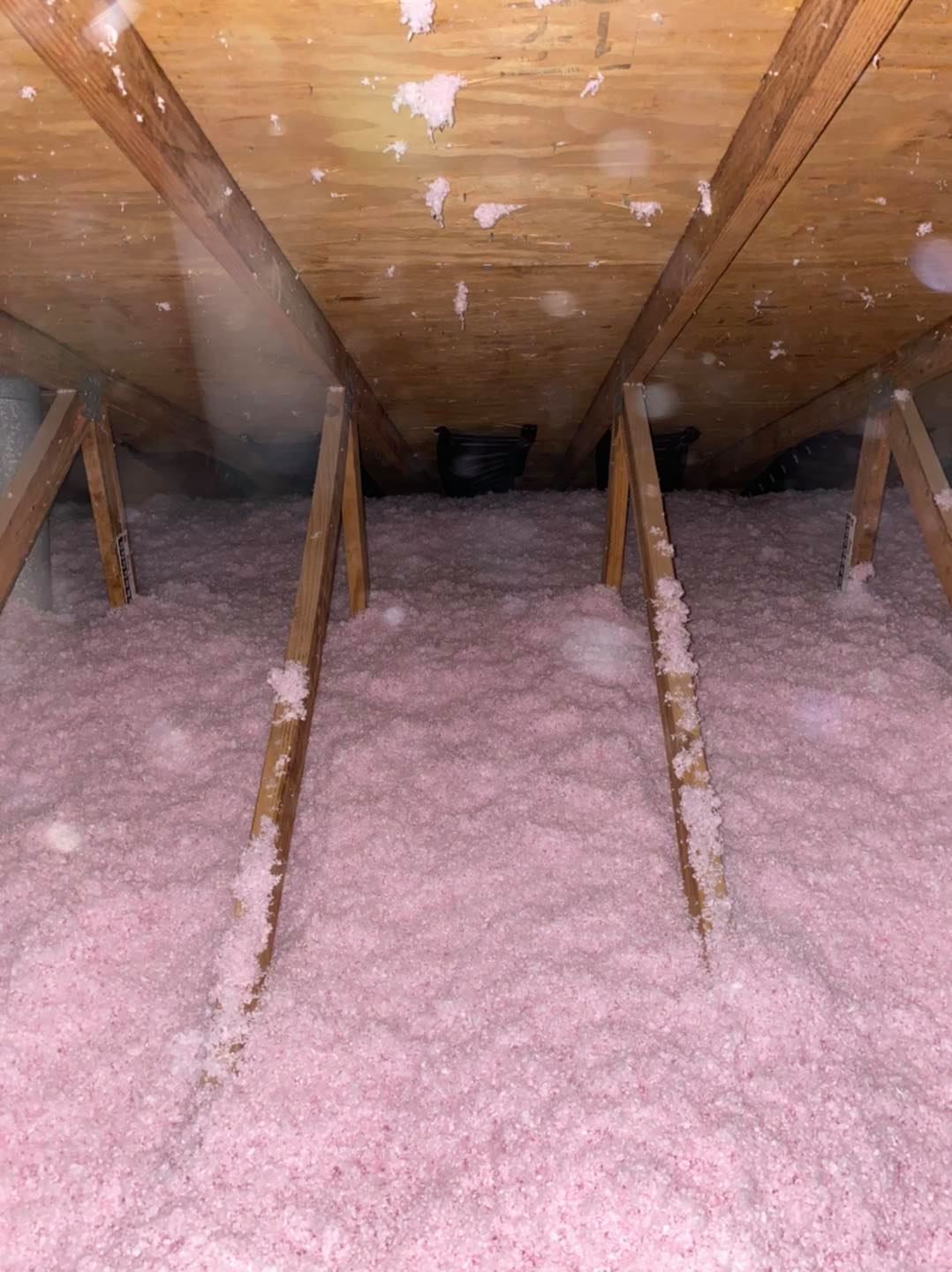 There is a lot of pink insulation in the attic of a house.