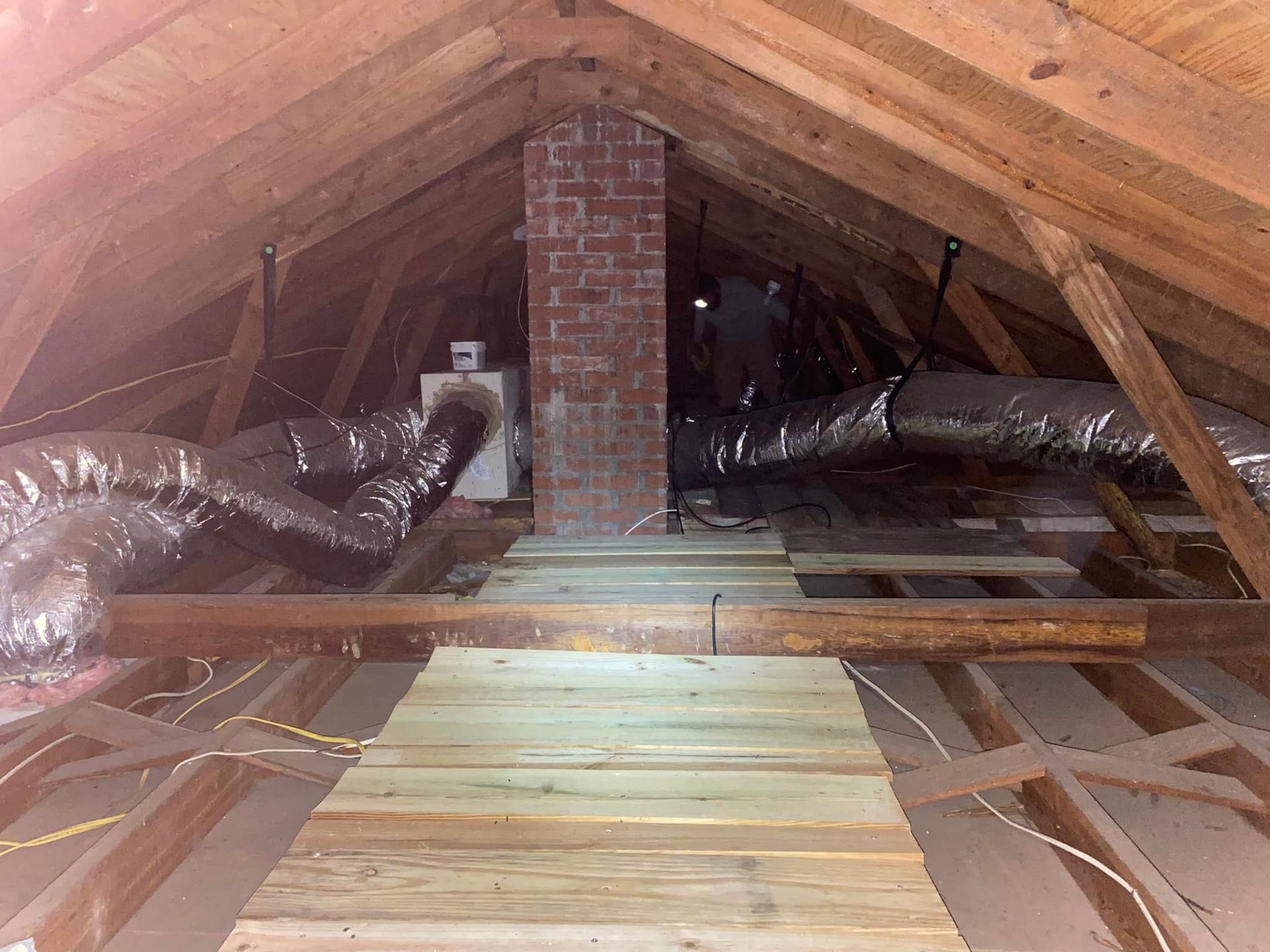 An attic with a wooden floor and a brick chimney.