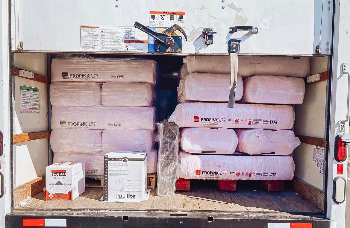 The back of a white truck is filled with bags and boxes