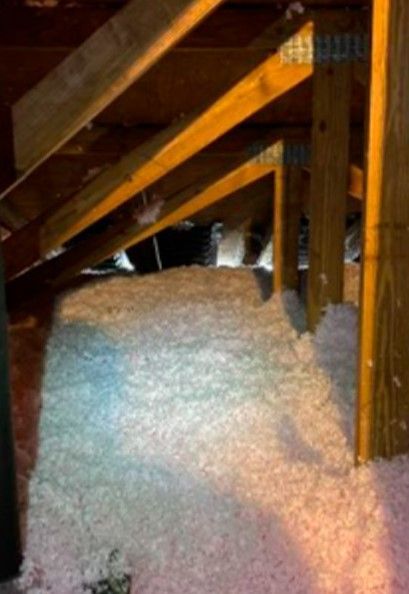 An attic with a lot of insulation and wooden beams