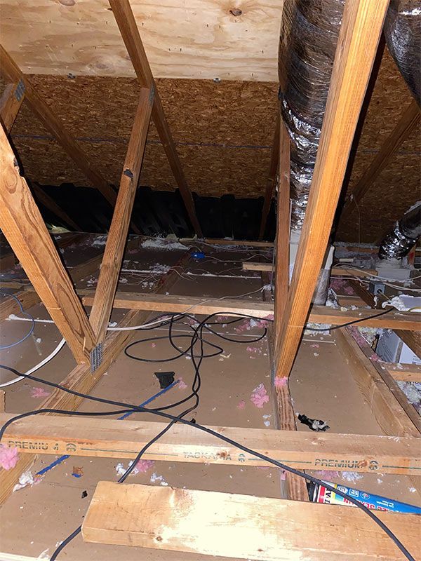 A wooden attic with a lot of wires hanging from it.