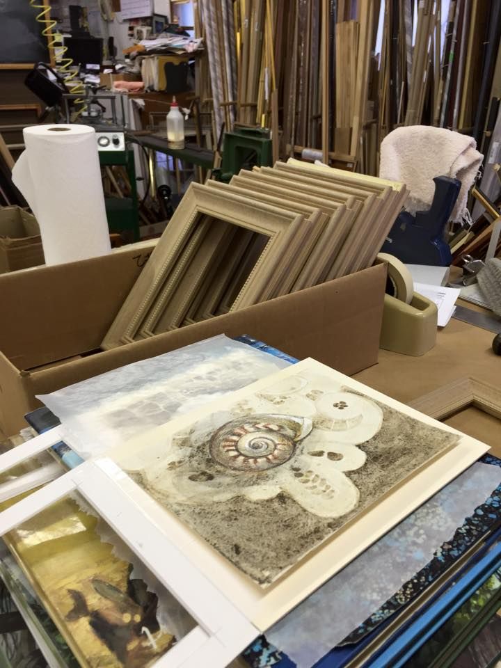 Landscape painting of a windswept pine tree on a rocky cliff overlooking a lake and forested landscape under a blue sky.