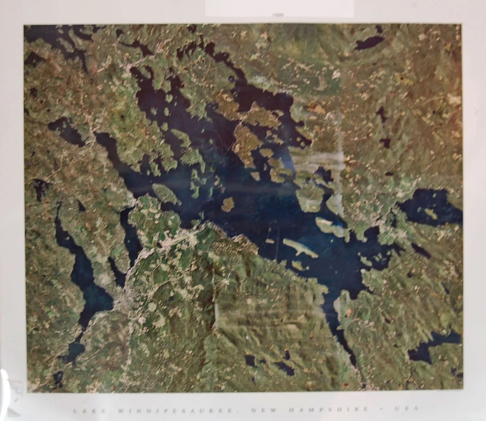 Aerial view of Lake Winnipesaukee, New Hampshire, with deep blue water and green, forested land.