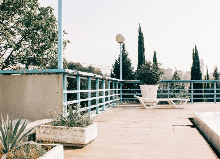 Terrace with blue railing and potted plants overlooking trees.