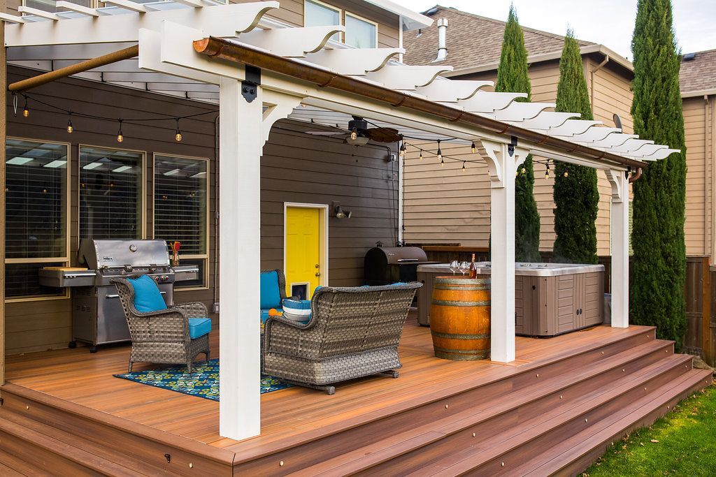 Outdoor patio with pergola, grill, seating, hot tub, and wooden deck.