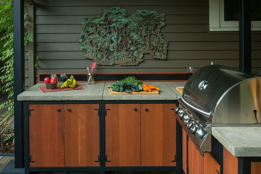 Outdoor kitchen with a grill, wooden cabinets, and concrete countertops.
