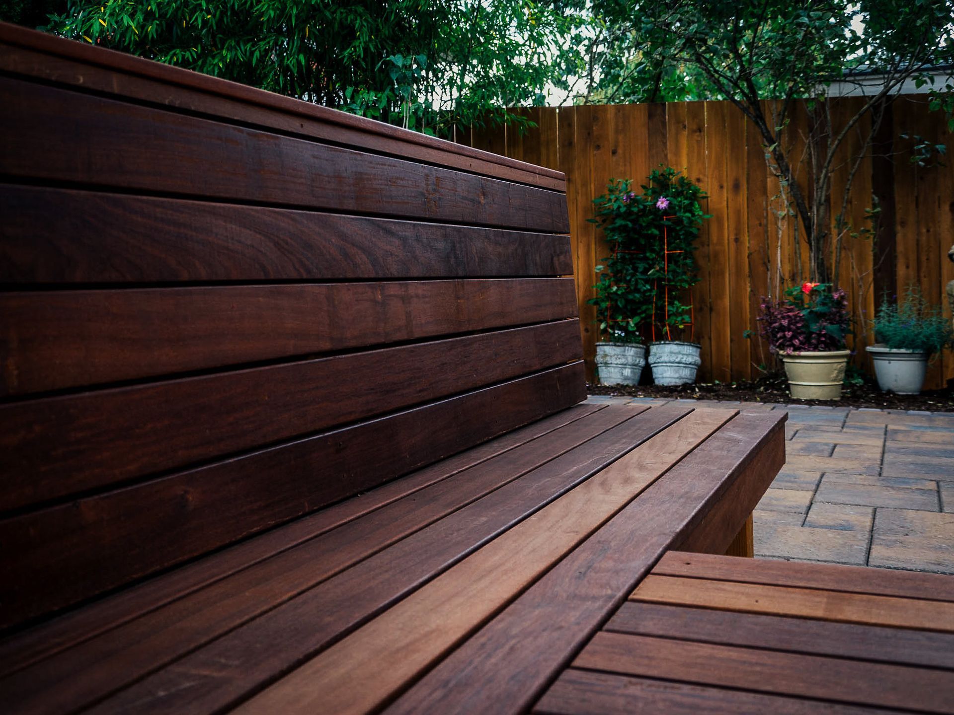 A wooden bench with a wooden fence in the background