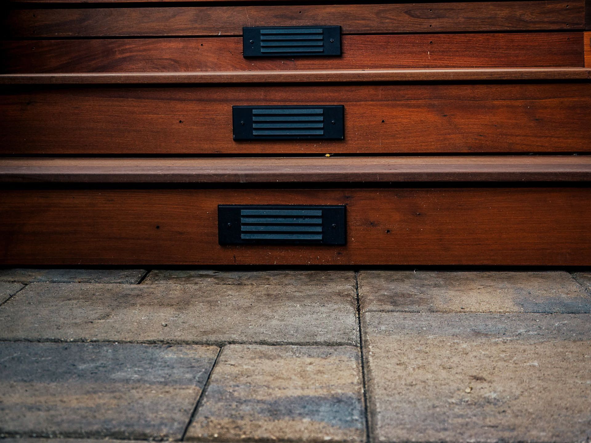 A set of wooden stairs with lights on the bottom steps