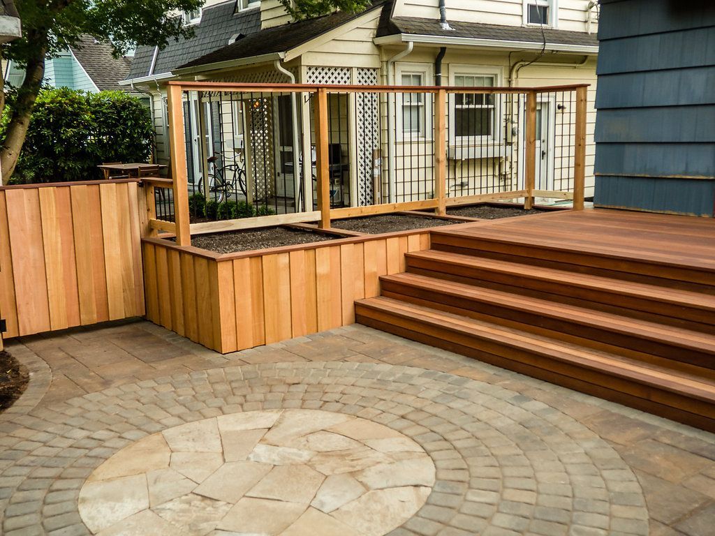 A wooden deck with stairs and a fence in front of a house.