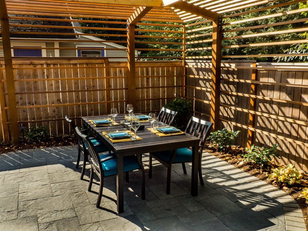 A patio with a table and chairs under a pergola.