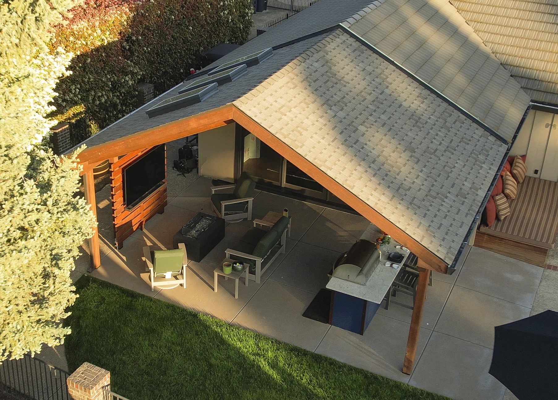 Patio with outdoor seating, grill, and a covered roof extending from a home.
