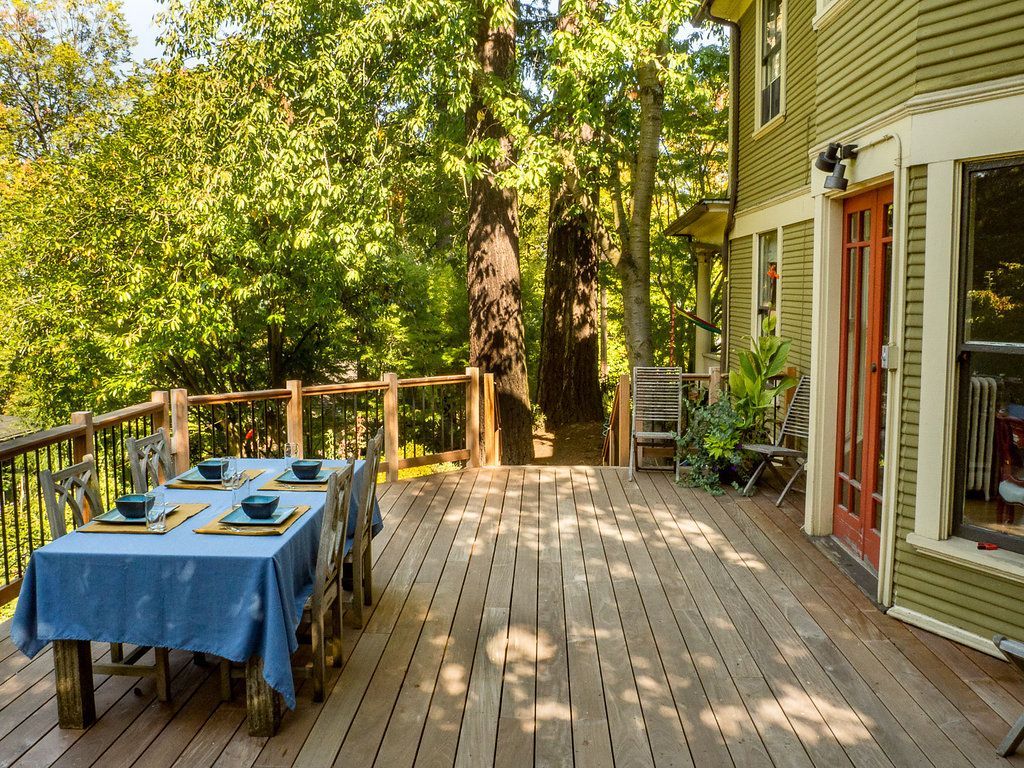Wooden deck with a table set for dining overlooking a lush forest.