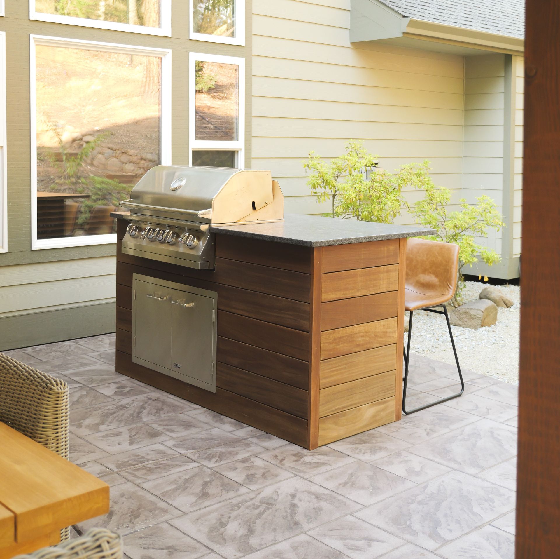 Outdoor grill island with stainless steel grill and cabinetry, set on patio.