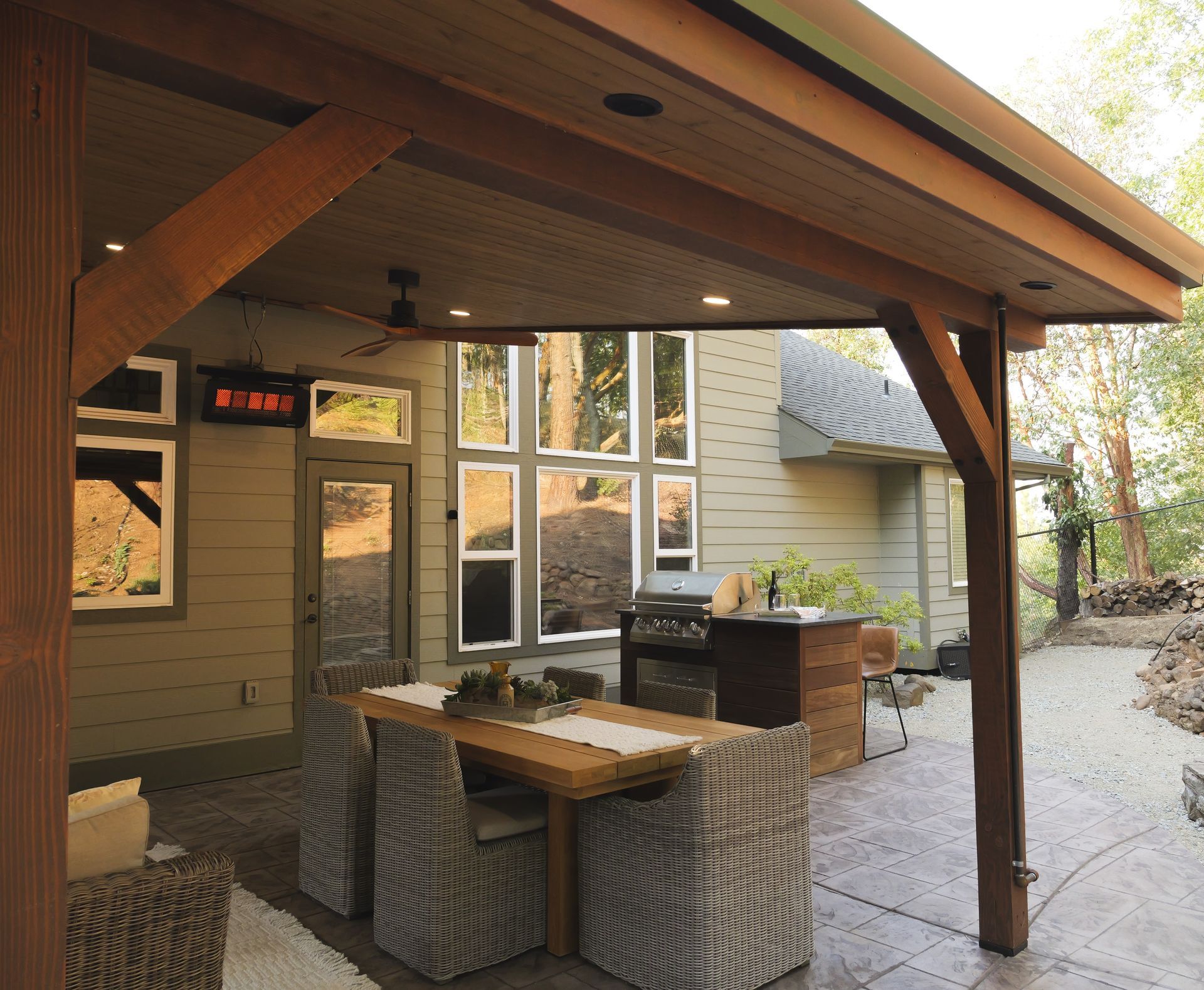 Patio with a wooden pergola, table, chairs, grill, and a view of a house.