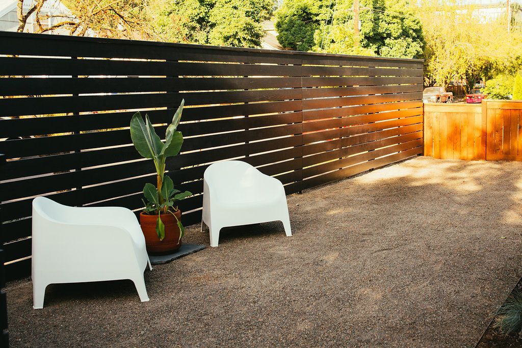 Two white chairs are sitting in front of a black fence.