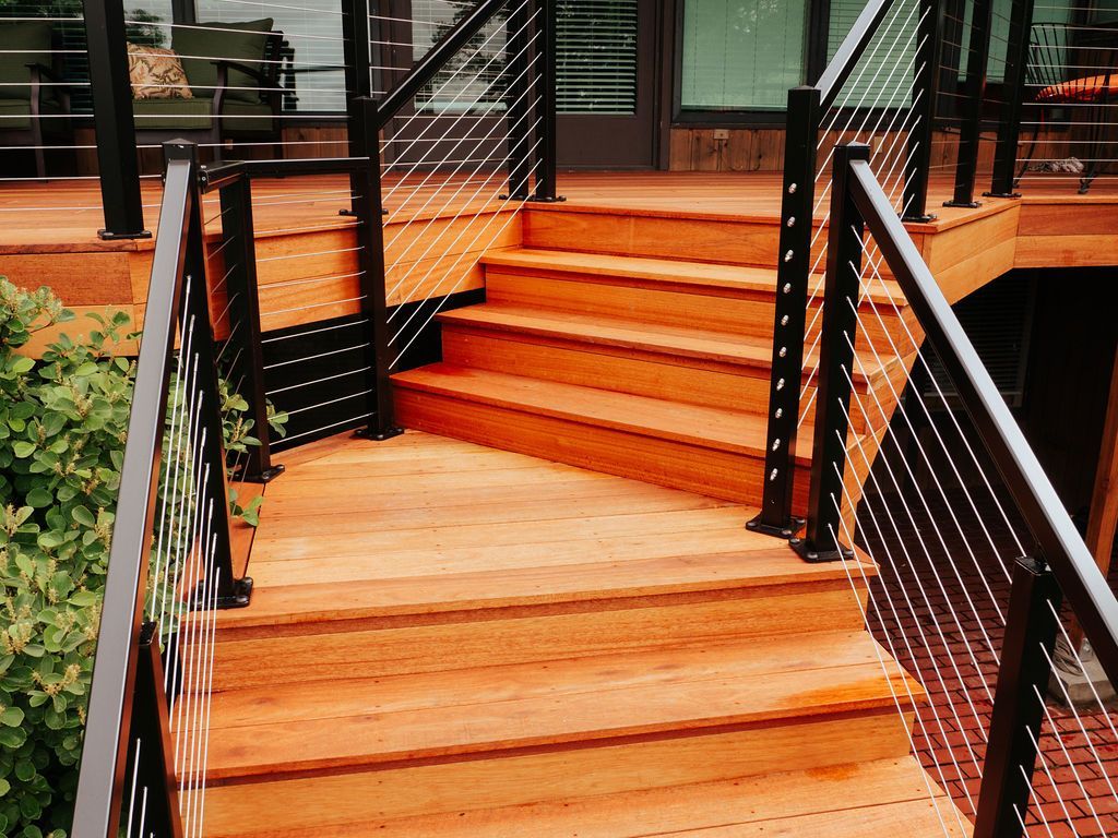 Wooden outdoor stairs with cable railings leading to a deck; natural light, brown wood tones.