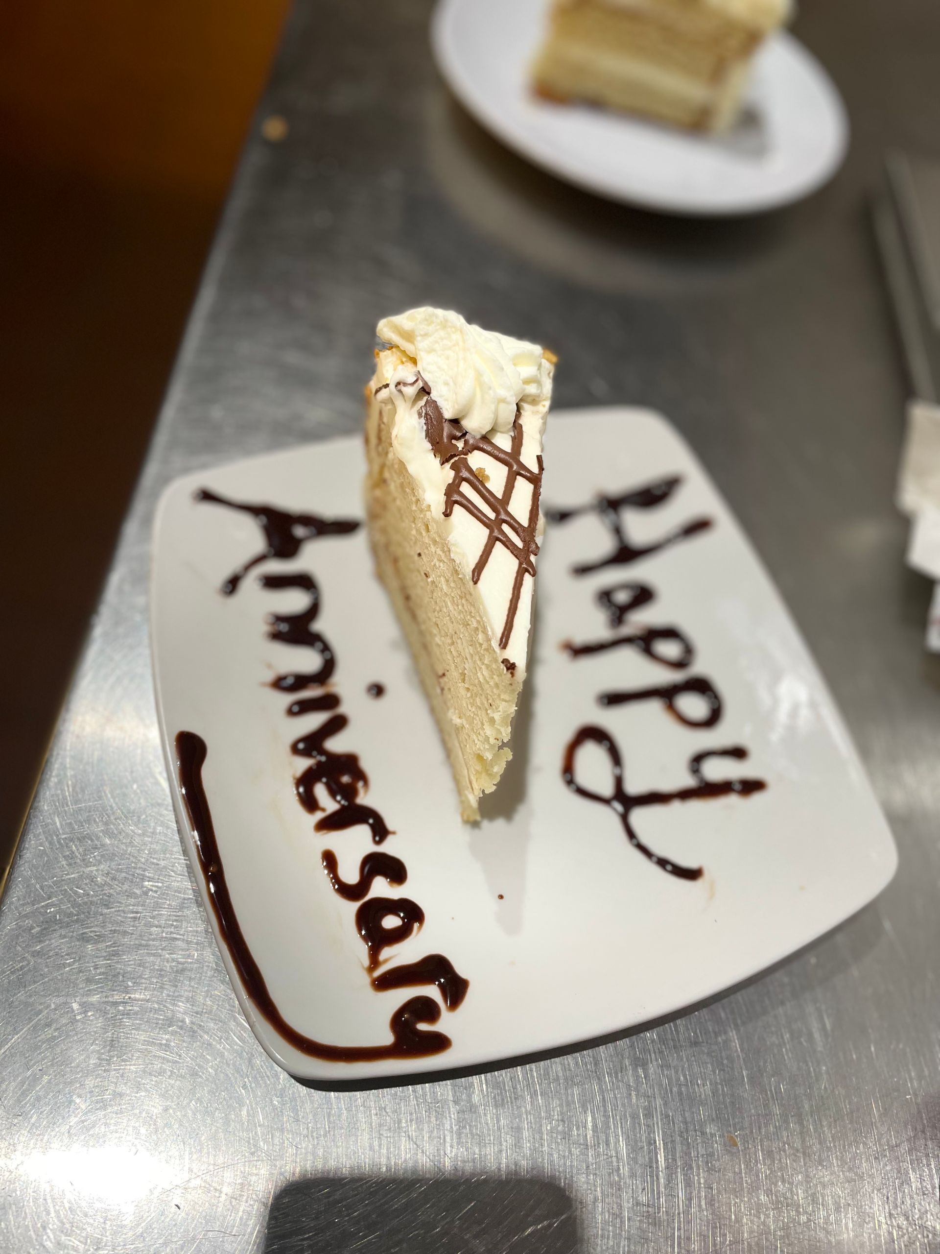 A slice of cake on a plate that says happy anniversary