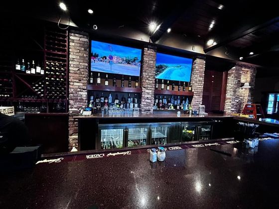 A bar in a restaurant with two televisions on the wall