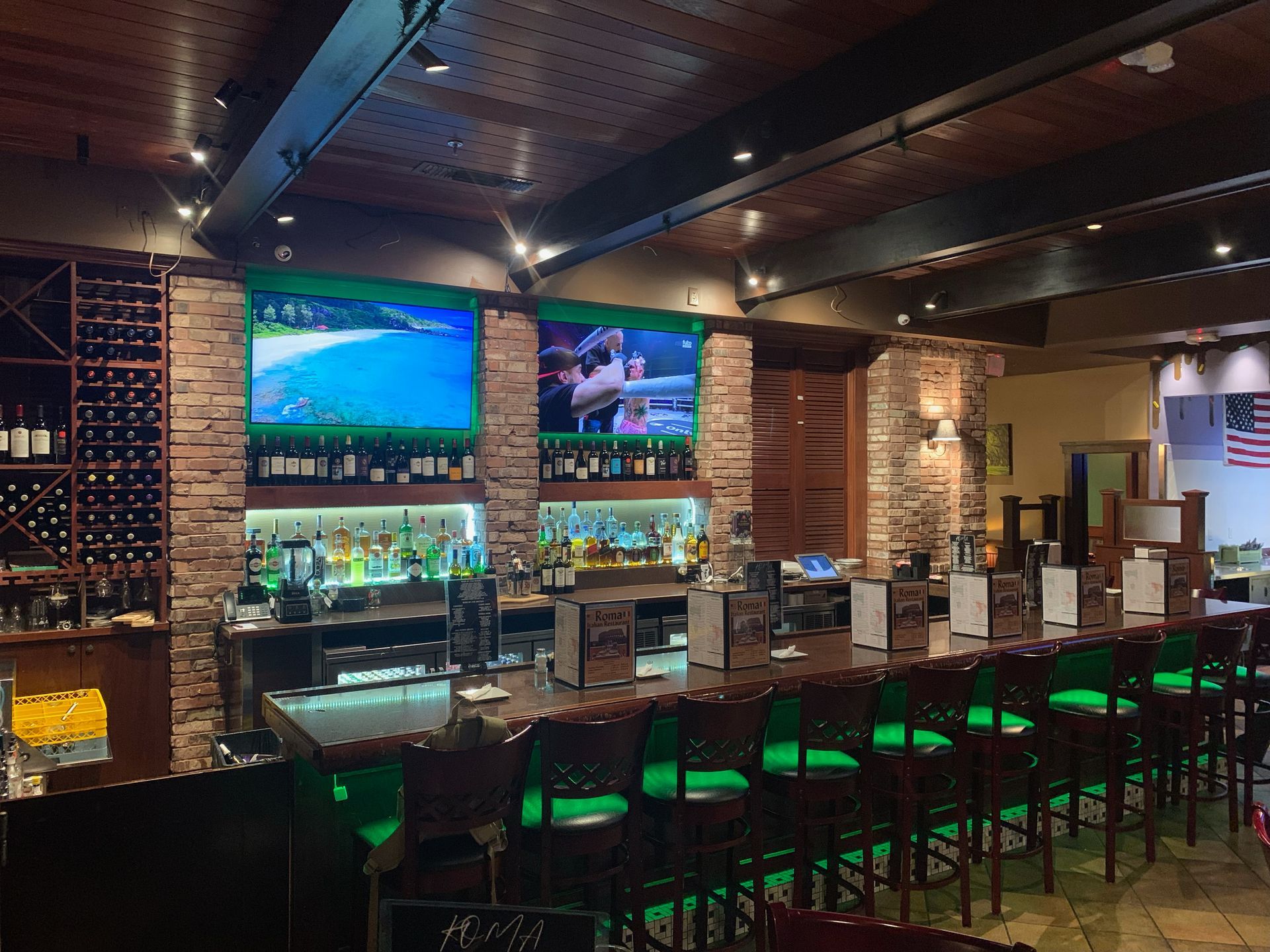 A restaurant with a long bar and green chairs.