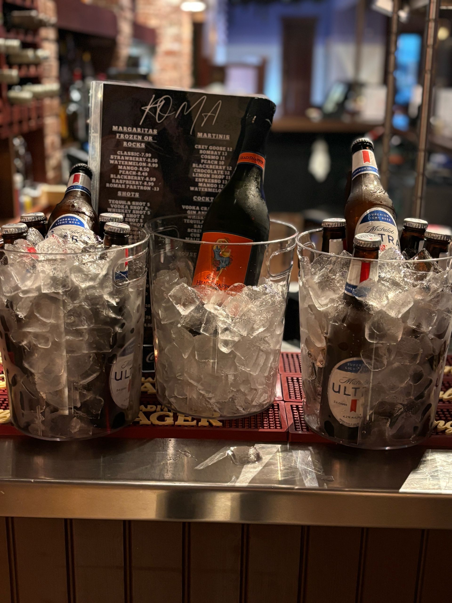 A bar with buckets of ice and bottles of beer on it.