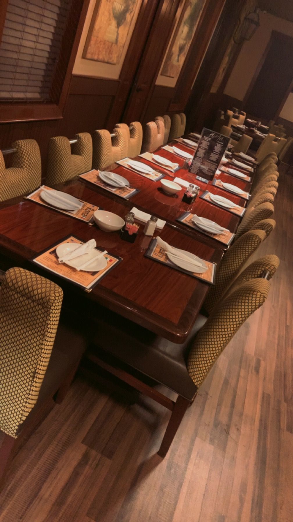 A long table with plates and napkins on it in a restaurant.