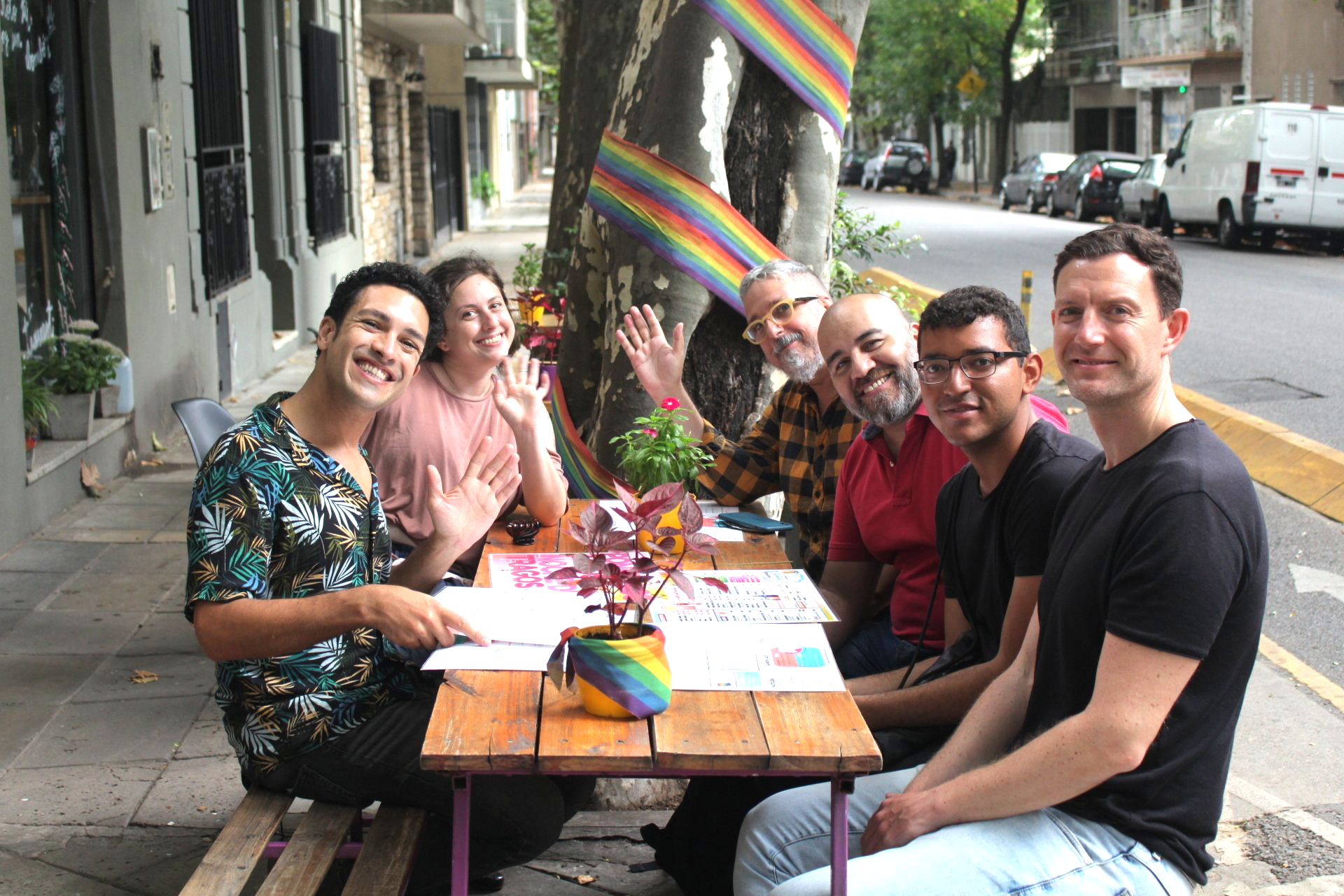 a group of men, women and a drag queen pose for the camera in a cafe