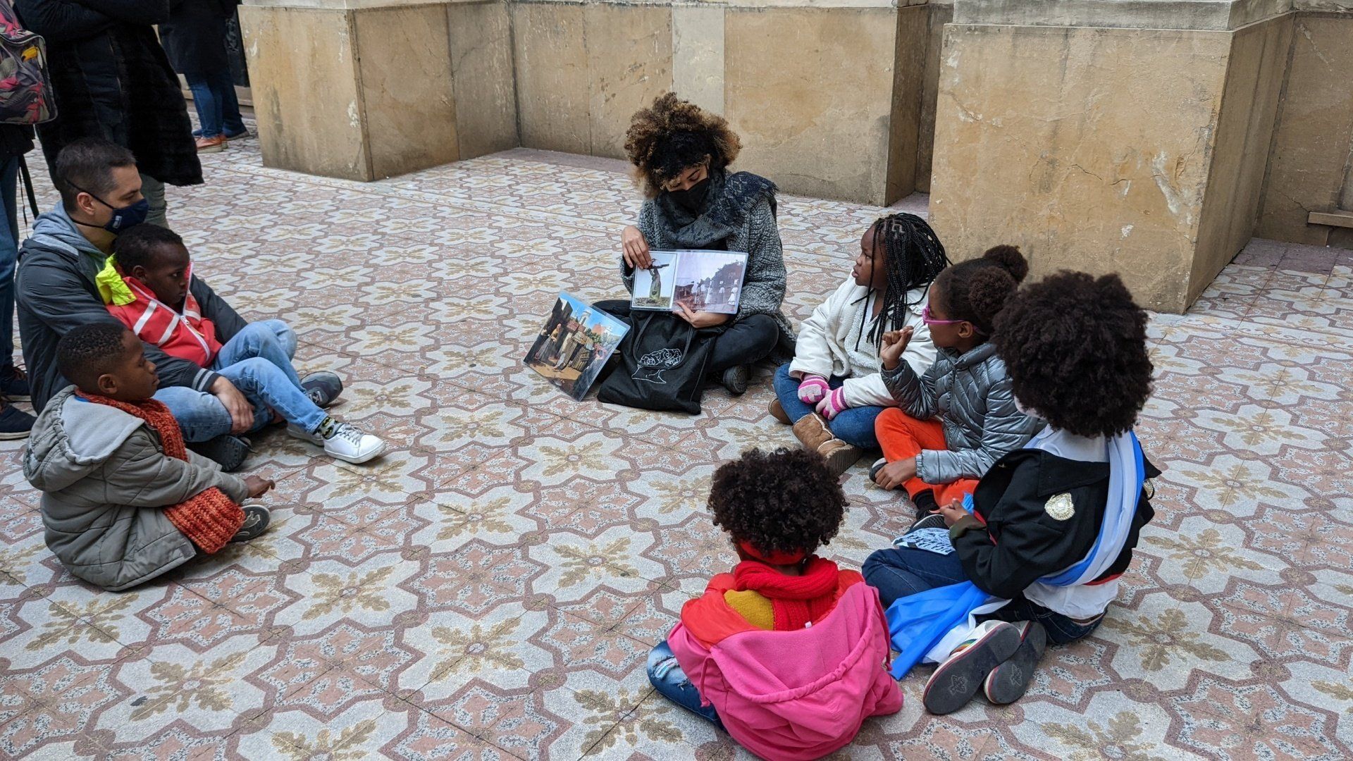 a group of afro argentine kids sit by a church with a guide explaining about Black History