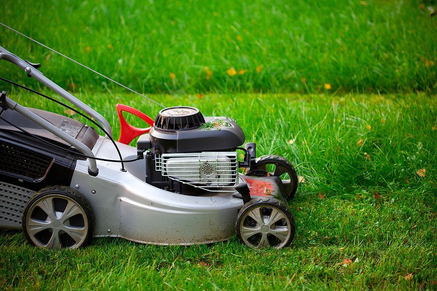 A lawn mower is sitting on top of a lush green lawn.