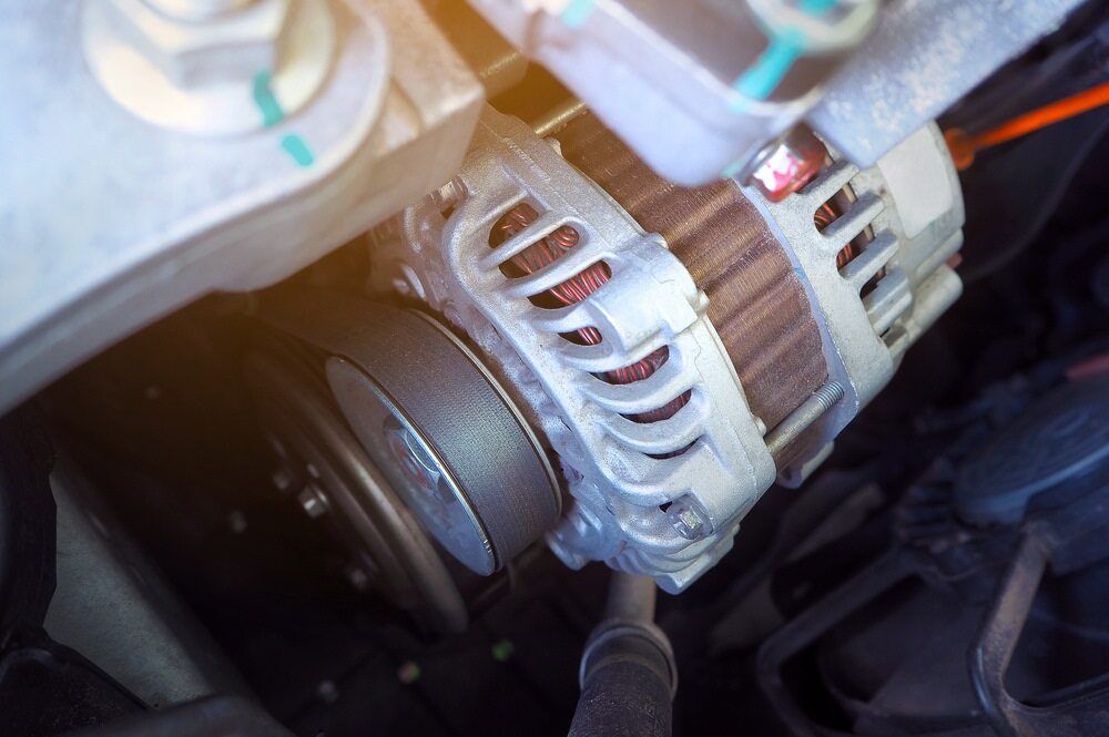 Car Alternator With Belt Attached, in Engine Bay. Grey Metal, Black Rubber Belt — H & E Auto Electrics in Noosaville, QLD
