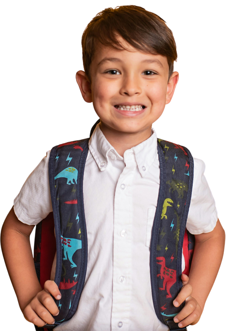 A young boy wearing a backpack with dinosaurs on it is smiling.