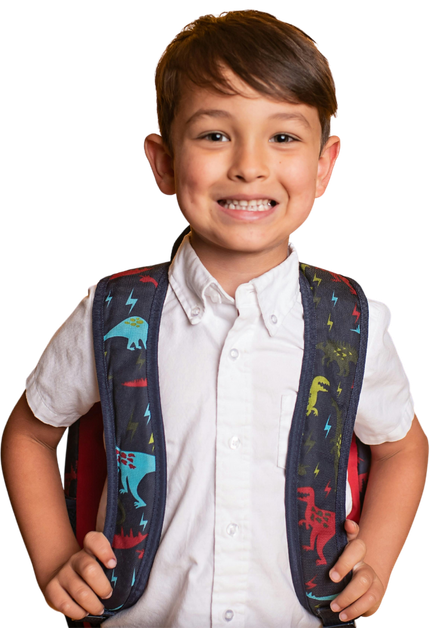 A young boy wearing a backpack with dinosaurs on it is smiling.