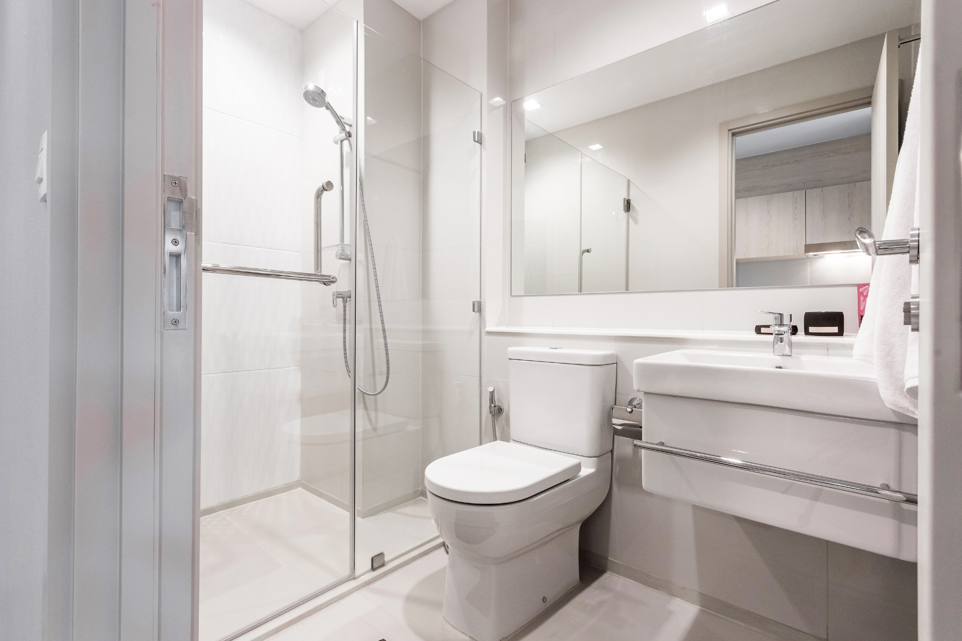 A bathroom with a toilet , sink , shower and mirror.