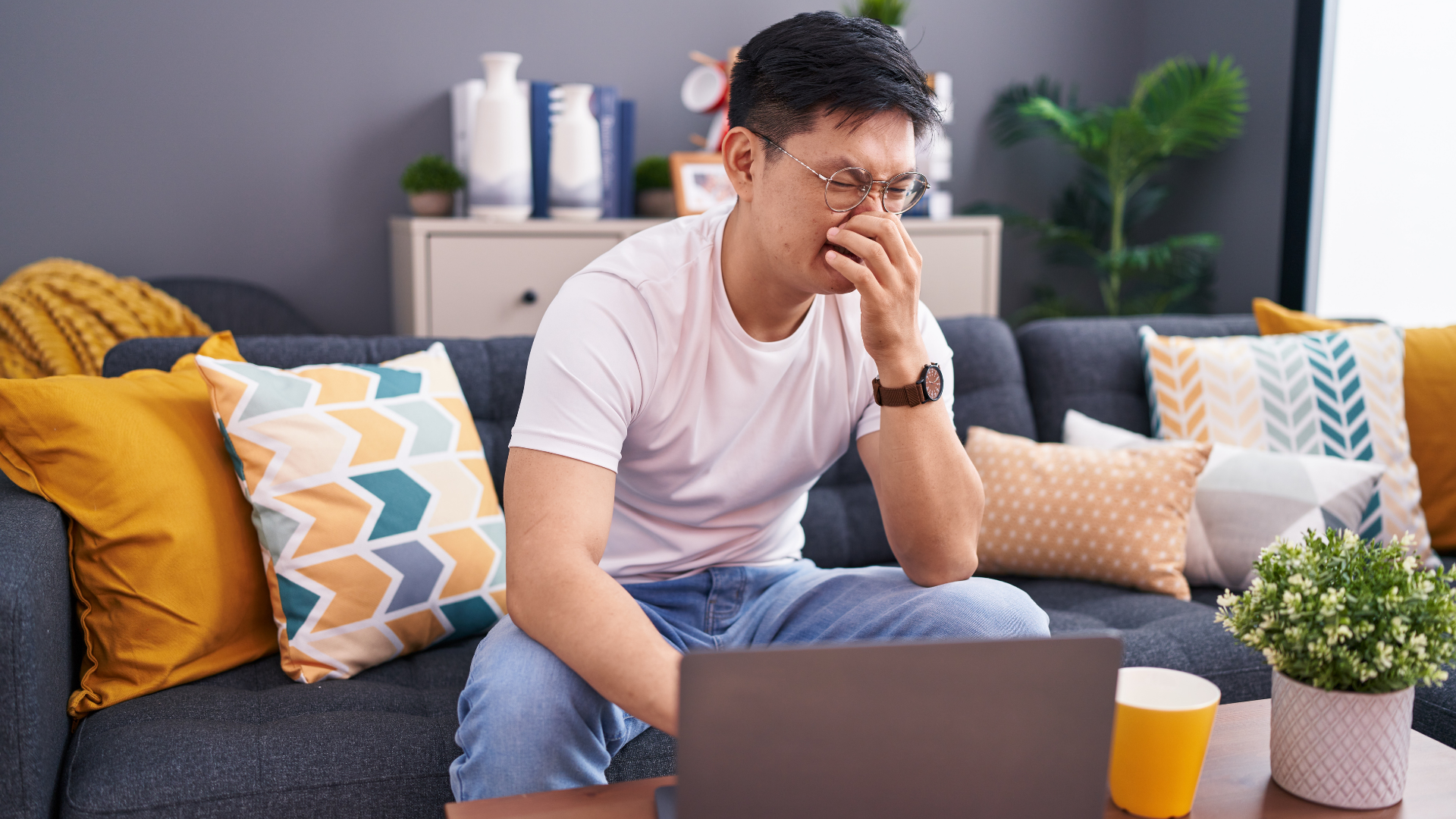 A man is sitting on a couch using a laptop computer.