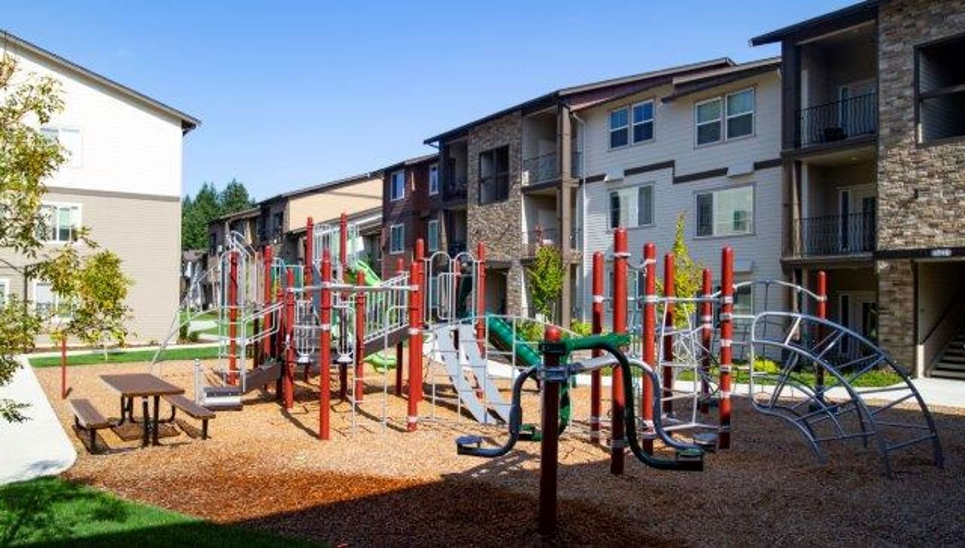 A playground with a table and chairs in front of a building.
